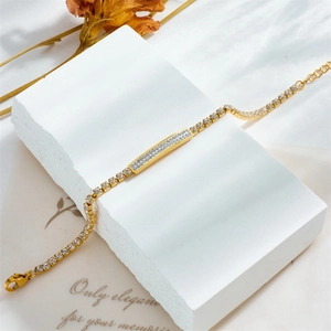 Elegantes goldenes Titanarmband mit kristallbesetztem Stabanhänger auf Display
