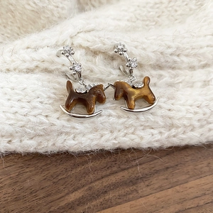 Macro shot of retro silver earrings with brown resin horse and cubic zirconia inlay