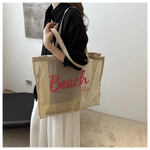 Detail of beige mesh tote bag with red Beach Vibes text carried by a female model