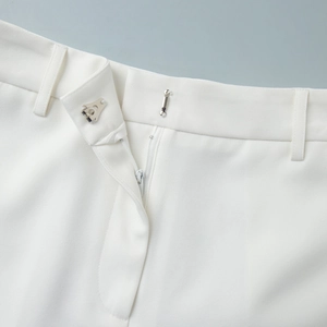 Detail of white suit shorts featuring metal hook closure and fine twill fabric texture