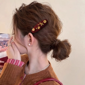 Detail of red velvet horse hair clip with gold fortune coin and star decorations