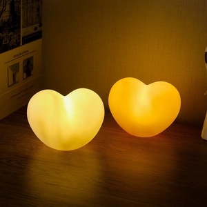 Heart-shaped night light with warm yellow glow on wooden table for festive gift