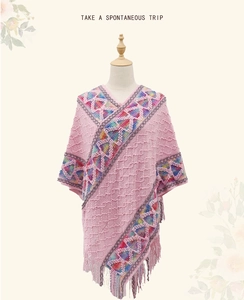 Close-up of pink boho knit poncho with colorful geometric patterns and long fringes