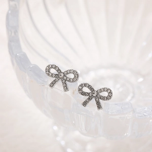 Sparkling silver bow knot stud earrings with cubic zirconia in a glass bowl