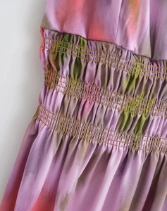 Detailed view of tie-dye print and ruched elastic waist on a sleeveless summer dress