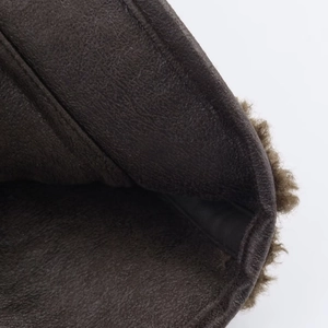 Detail view of dark brown leather jacket with soft brown faux shearling lining texture