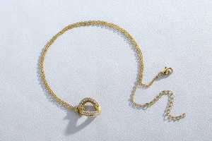Detailed macro view of a gold double-layered necklace featuring a sparkling heart pendant