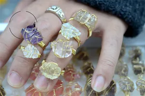 Detail of handmade wire-wrapped natural crystal rings with raw amethyst and quartz stones