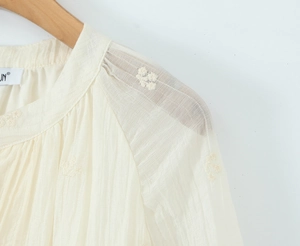 Détail de broderie florale élégante et de mousseline texturée sur une robe blanche