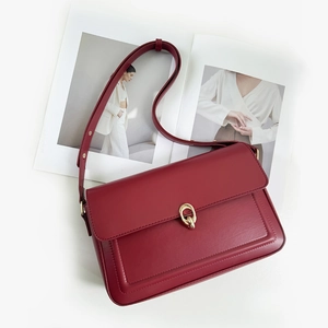Detail view of burgundy leather handbag with gold chain lock on a fashion magazine