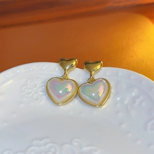 Close-up of heart-shaped pearl earrings with iridescent finish and gold metal borders