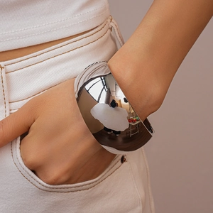 Close-up of a wide irregular silver cuff bracelet with a polished mirror finish on a wrist