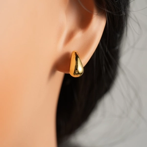 Detailed close-up of polished gold teardrop stud earrings with a shiny mirror finish