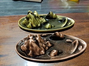 Detailed close-up of mountain peak incense burners in bronze and gold metal finishes