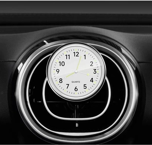 Close-up of white quartz car clock mounted on dashboard air vent with metal rim