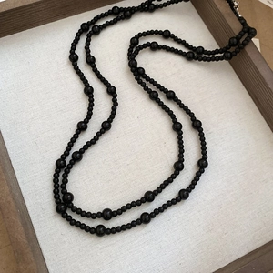 Detail of black beaded necklace with silver clasp on a wooden tray display