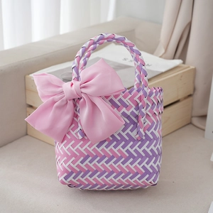 Detail of colorful woven tote bag featuring a large pink bow on a rustic background