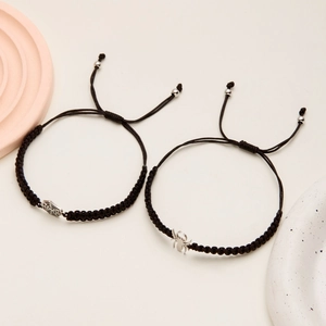 Detail view of handmade woven black bracelets with silver spider and web charms