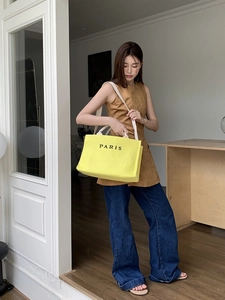 Fashionable yellow woven straw tote bag with Paris lettering and white straps on model