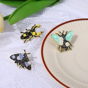 Detailed view of enamel insect brooches featuring beetles and moths on lace background