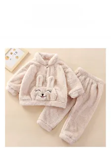 Detailed flat lay of beige flannel baby pajama set with 3D bunny ears and soft texture