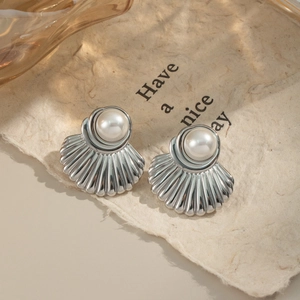 Macro di orecchini a conchiglia in argento con perle su un biglietto d'auguri beige