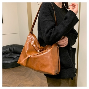 Detail of vintage brown oil leather tote bag showing gold buckle and premium texture