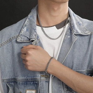 Mens silver stainless steel cuban link chain and bracelet set worn with denim jacket