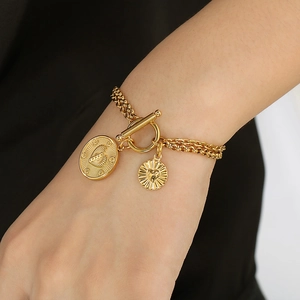 Golden paperclip chain bracelet with heart pendants and OT buckle on a female wrist