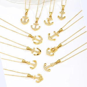 Dettaglio di vari ciondoli a forma di ancora placcati oro 18K con cristalli zirconi