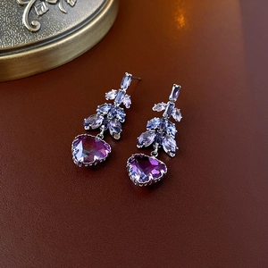 Détail de boucles d'oreilles fleuries avec pierres en forme de cœur dégradé violet