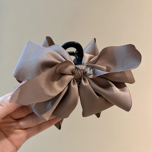 Close-up of large satin bow hair claw clip with rhinestone detail in a soft brownish pink