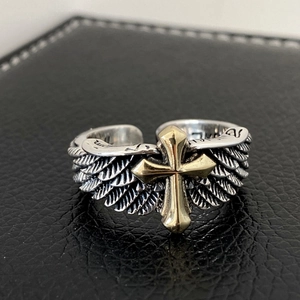 Macro shot of silver retro cross ring with gold feather accents on black leather