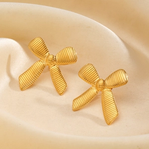 Fashion 18K gold plated bow earrings with textured stripes on elegant beige silk