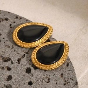 Vue macro de boucles d'oreilles vintage en or avec texture corde et pierre noire
