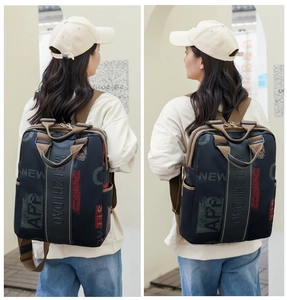 Detail of navy blue backpack with letter print and brown straps shown on a model
