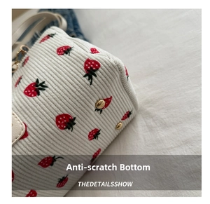 Close-up of strawberry print corduroy bag bottom featuring gold protective studs