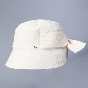 Detail of elegant beige bucket hat featuring textured fabric and a chic bow decoration