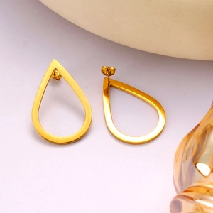 Macro shot of minimalist hollow teardrop earrings in polished gold finish on purple background