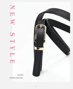 Detail of slim black PU leather belt with premium gold alloy buckle and smooth texture