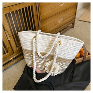Detail of woven tote bag featuring floral daisy charm and beige cotton rope texture