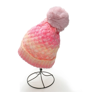 Close-up of pink and yellow gradient knit texture and soft faux fur pom pom