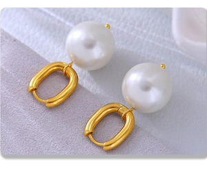 Macro view of white round pearl earrings with golden U-shaped stainless steel clasps
