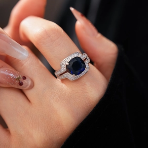 Gros plan d'une bague en zircon bleu profond avec pavé étincelant porté par un modèle