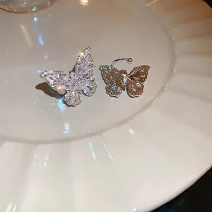 Sparkling butterfly ear cuff with silver zircon inlay on a textured white ceramic plate