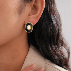 Vintage gold frame black enamel stud earrings with central pearl worn by a model