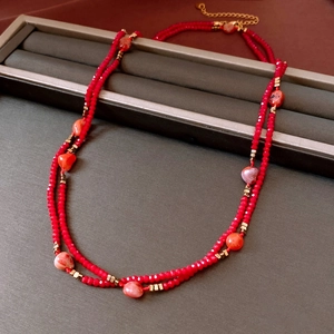 Close-up of double-layer beaded necklace featuring red crystals and gold metal accents