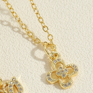 Macro view of gold four-leaf flower pendant with pavé set cubic zirconia and fine chain