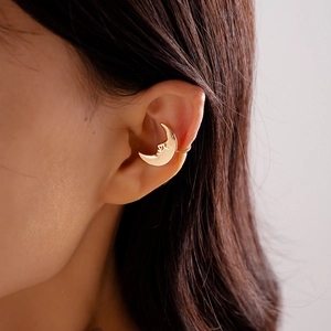 Detailed close-up of a golden crescent moon ear cuff with vintage face engraving
