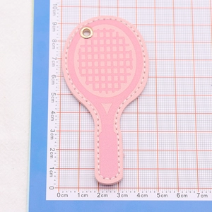Detailed view of pink leather racket keychain with white stitching on blue cutting mat